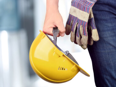 Travailleur sur un site de construction avec casque à la main et gants attachés à la taille 1