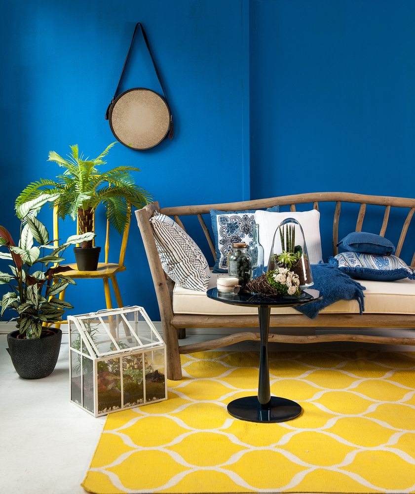 Design intérieur avec murs bleus, sol blanc et tapis jaune pour apporter de la vie