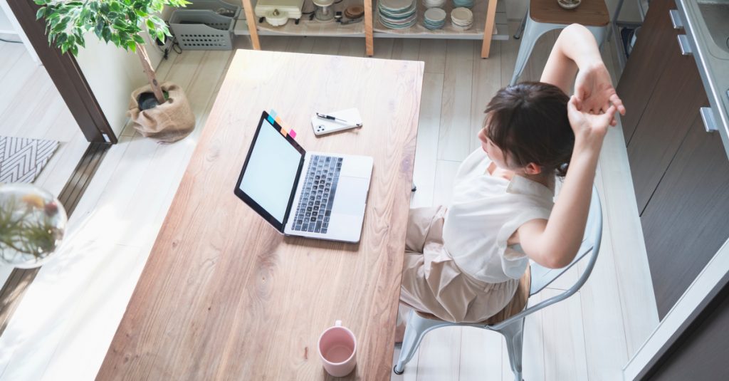 Femme en train de s'étirer pendant sa journée de télétravail dans la cuisine
