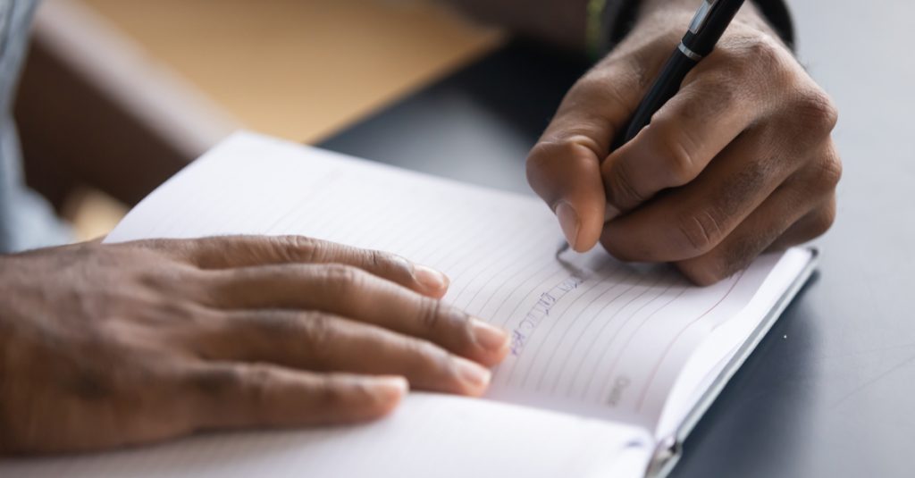 Un homme en train d'écrire les objectifs de sa journée de télétravail
