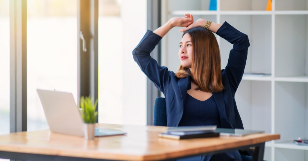 Femme en train de s'étirer et faire une pause pendant sa journée de télétravail