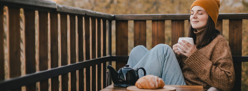 Jeune femme buvant un thé sur sa terrasse d'automne