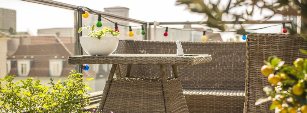 Balcon avec plantes et mobilier en rotin