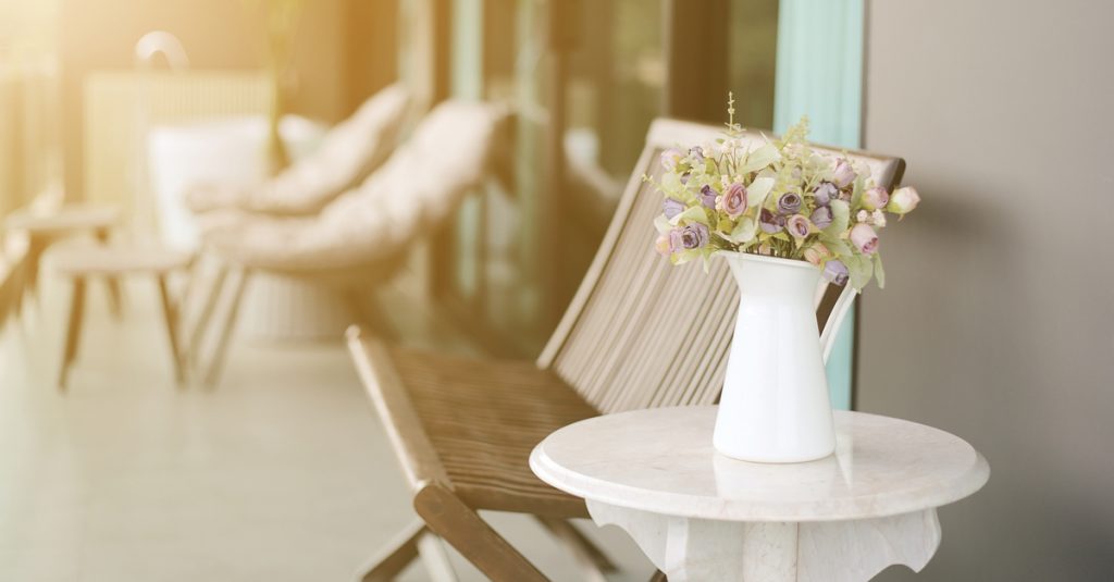 Pot de fleurs au premier plan et balcon ensoleillé avec sièges en bois