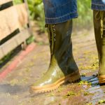 Personnes en bottes de pluie en train de nettoyer sa terrasse en bois au jet d’eau