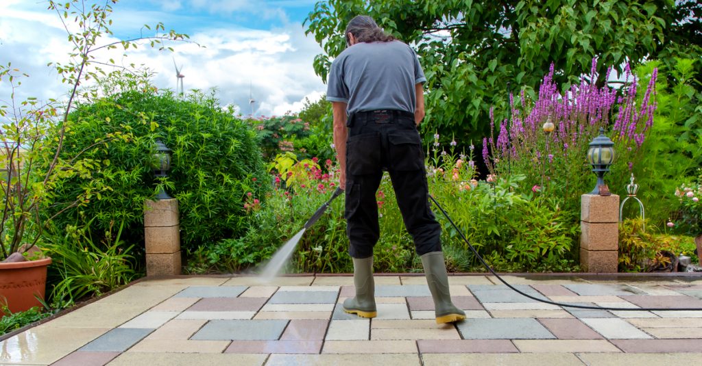 Personne en train de rincer sa terrasse au jet d’eau