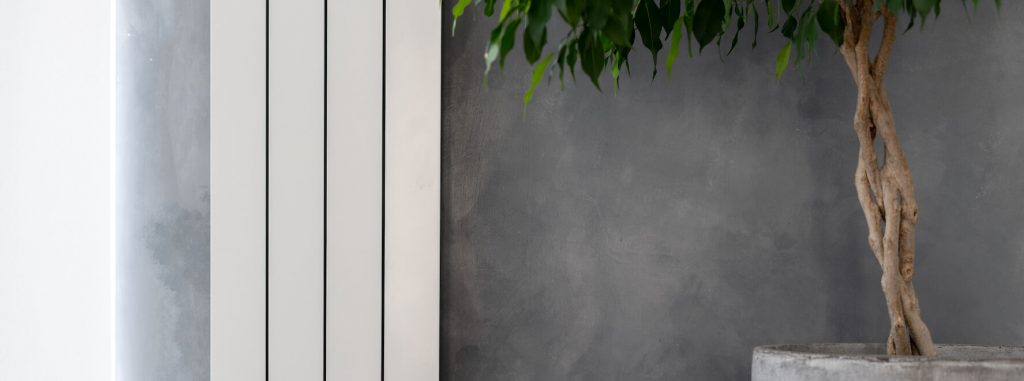 Radiateur électrique vertical sur mur de salon gris