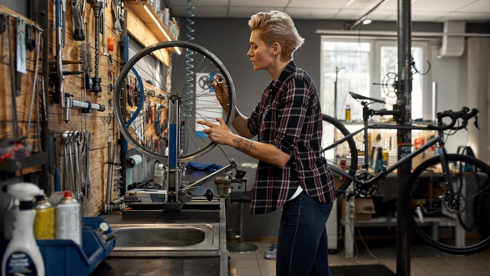 Femme avec roue de vélo au-dessus du lavabo dans son atelier de bricolage
