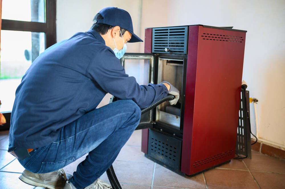 Professionnel certifié en train de faire l'entretien annuel d'un poêle à granulés