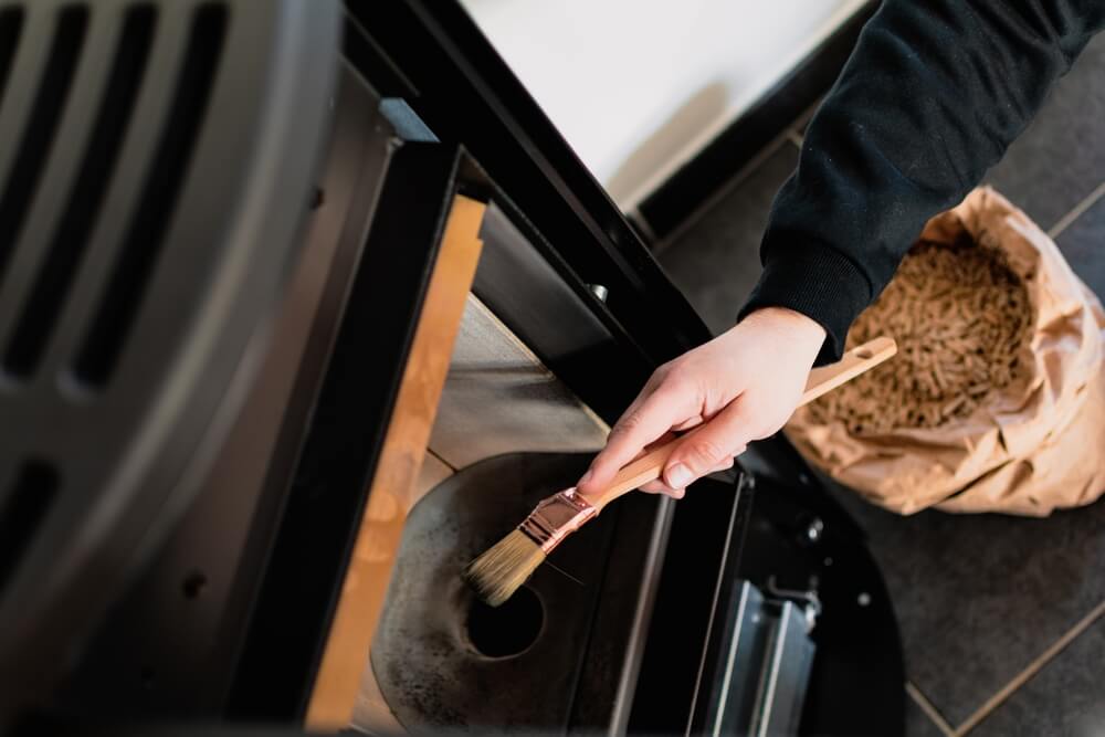 Homme en train de nettoyer un poêle à granulés avec une brosse