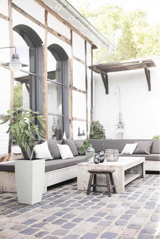 Grand pot extérieur sur terrasse en pierres pavées avec salon de jardin