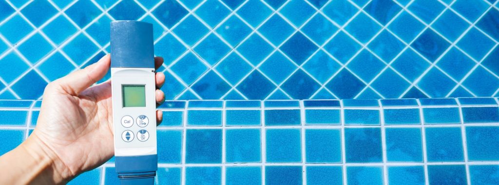 Main qui tient un testeur électronique au-dessus d’une piscine