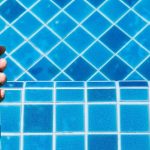 Main qui tient un testeur électronique au-dessus d’une piscine