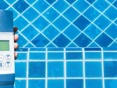 Main qui tient un testeur électronique au-dessus d’une piscine