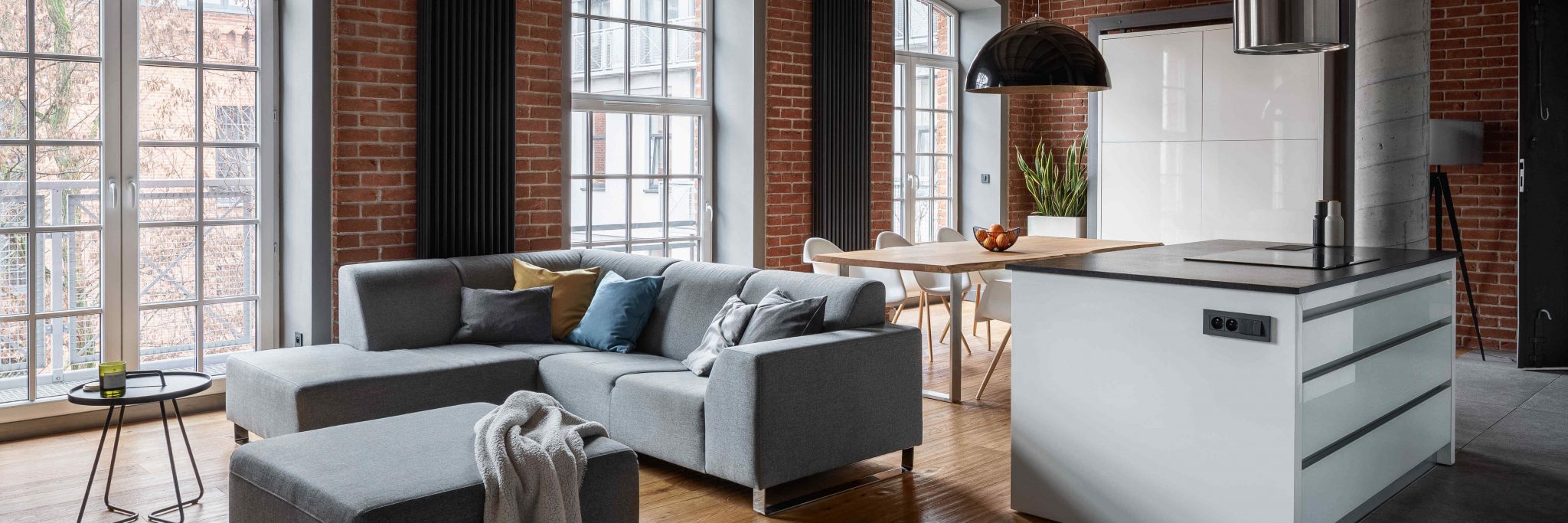 Salon industriel avec murs en briques, table en bois et ilôt de cuisine moderne